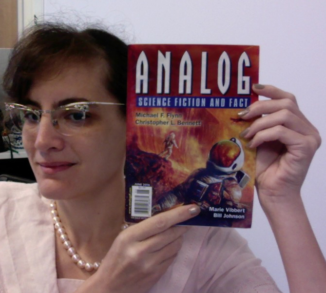 Marie holds up an issue of Analog, pointing to her name on the cover.