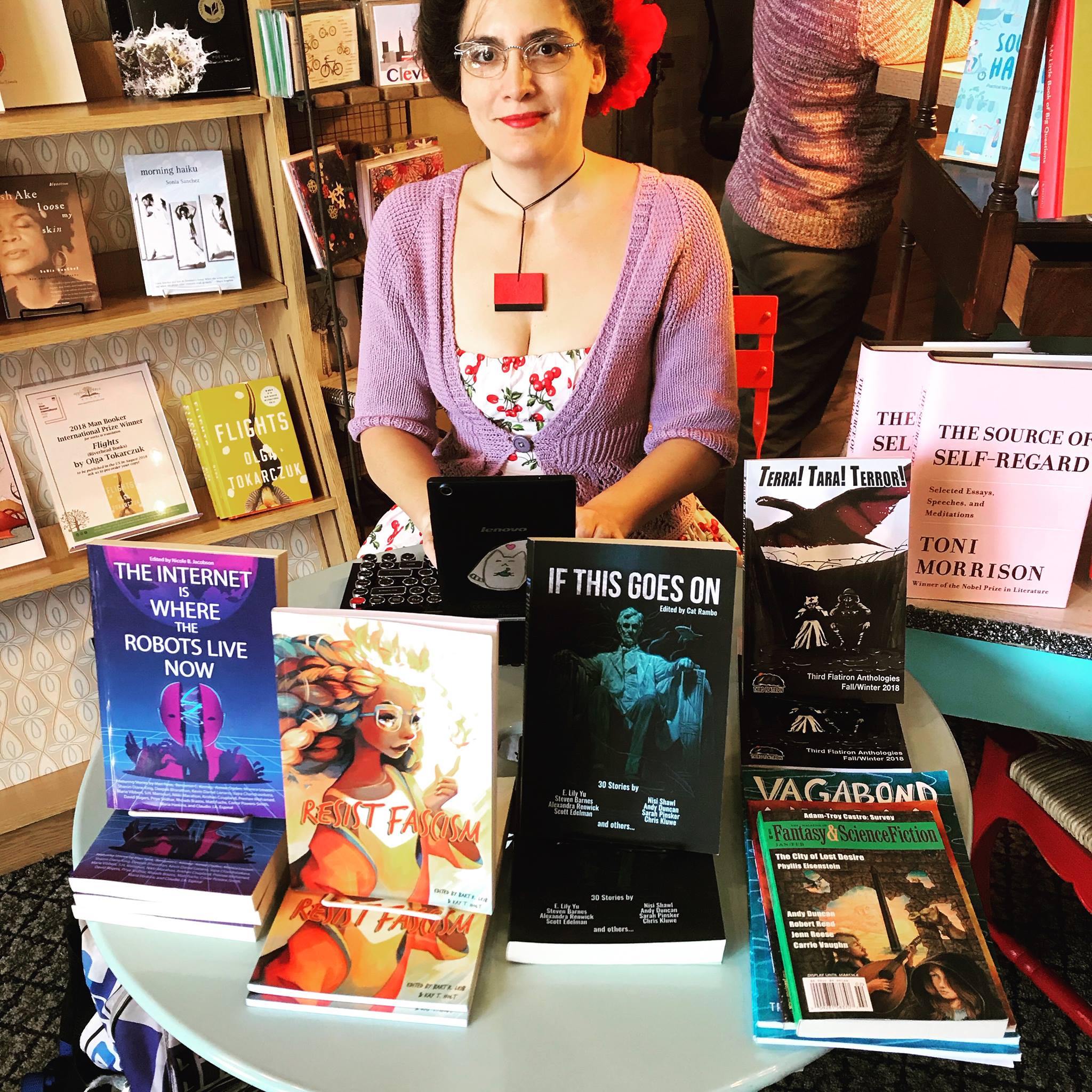 Marie sitting at a table covered with anthologies in a bookstore