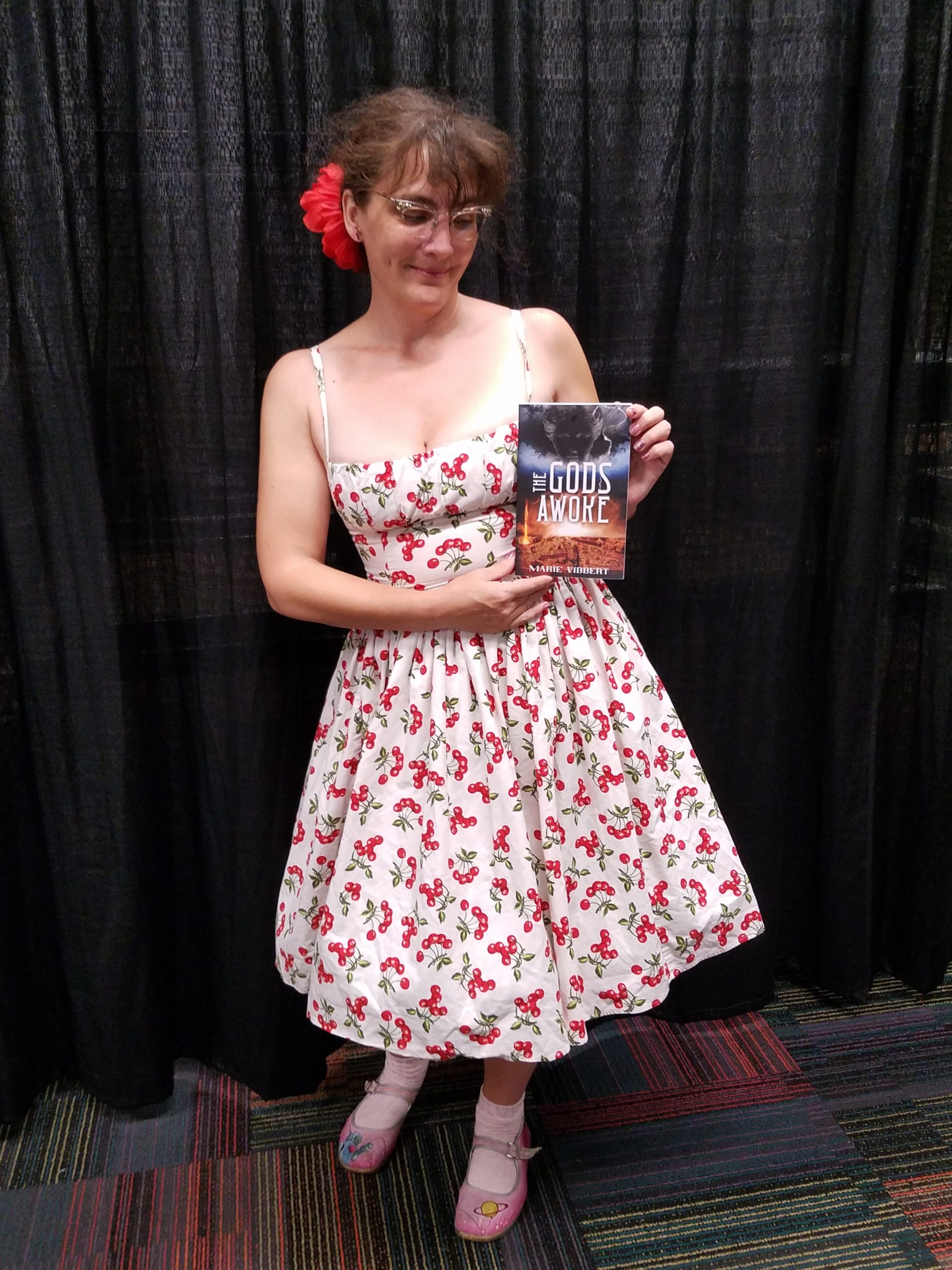 Marie holds her book in front of a plain black curtain