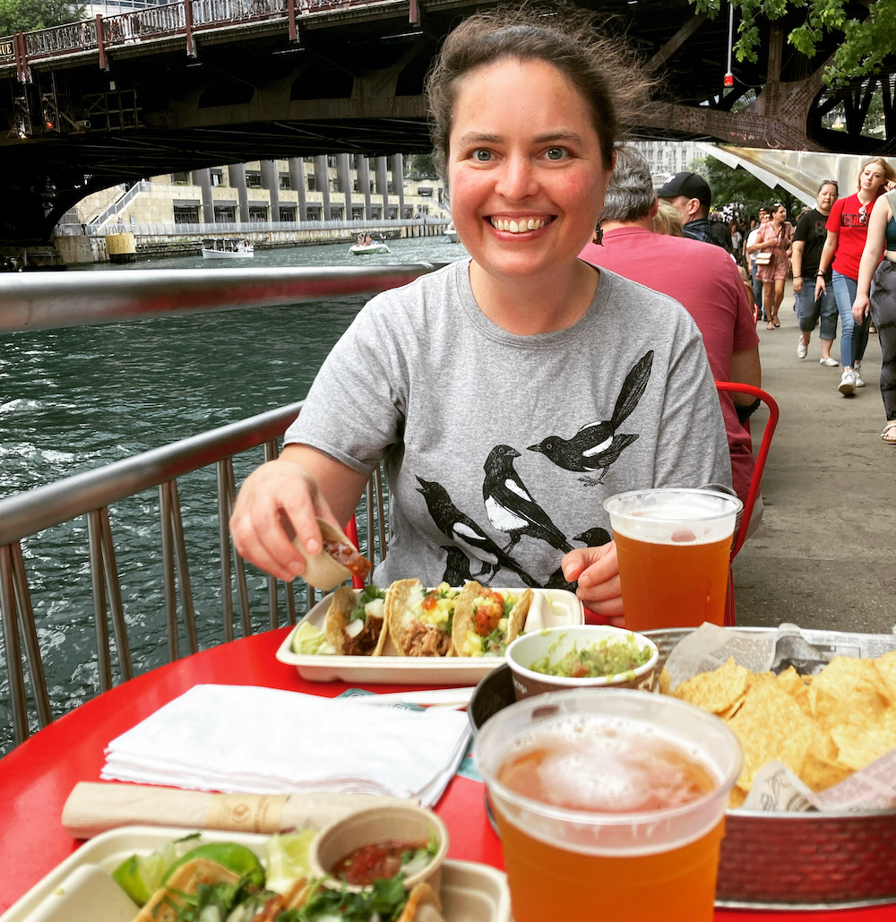 Usula Whitcher eating tacos and beer by the Chicago River