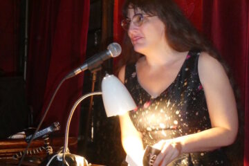 Marie reading at a podium in a red room