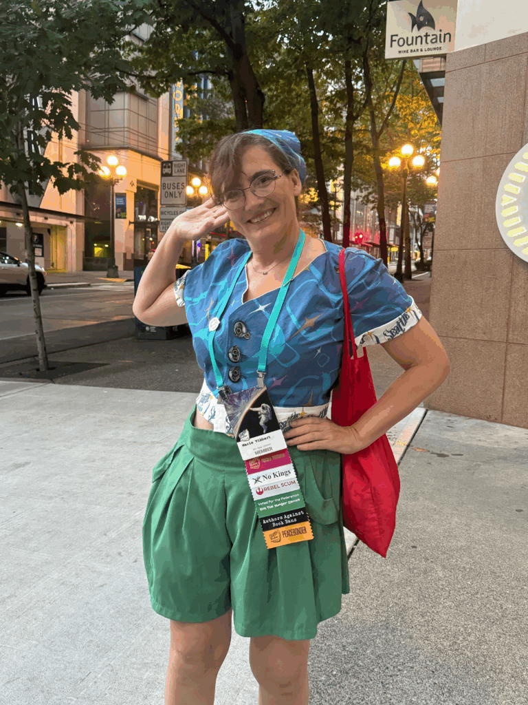 Woman in blue headscarf and blue blouse posing for a photo on a street corner soft streetlight coming on in the background 